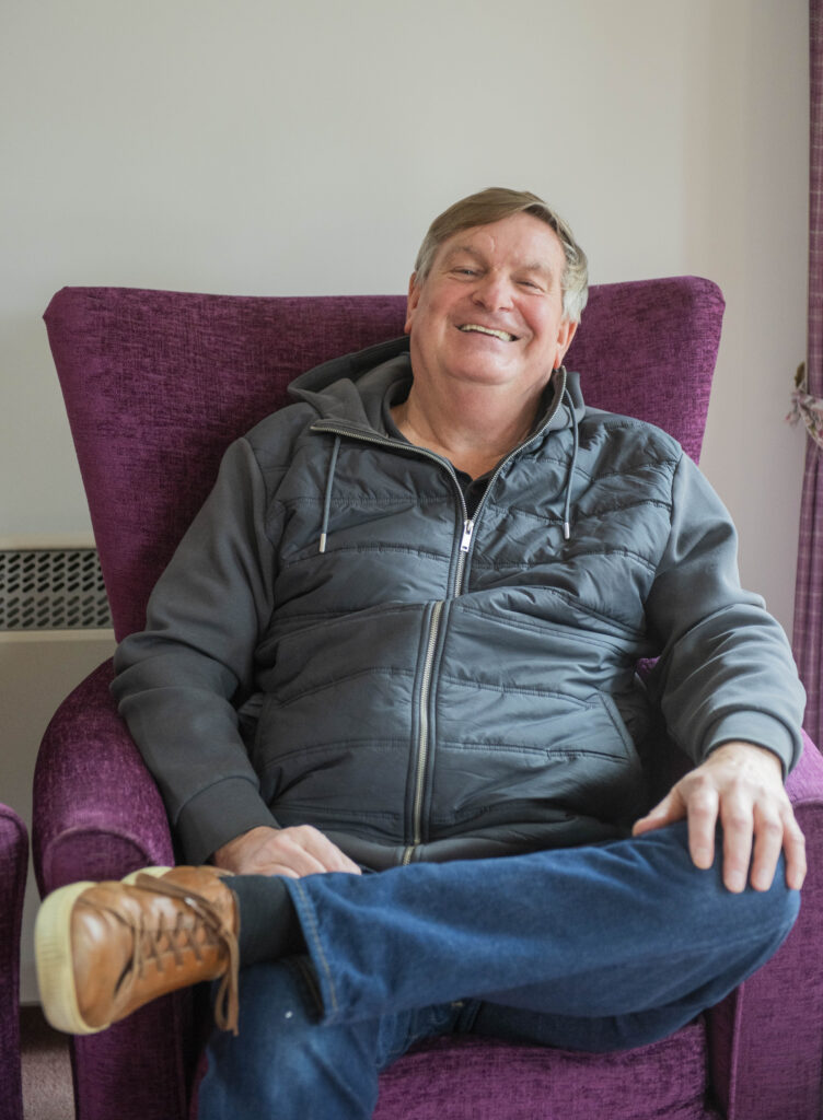 Steve Hudson, retiree sat in communal lounge, Rose Court, Littlehampton