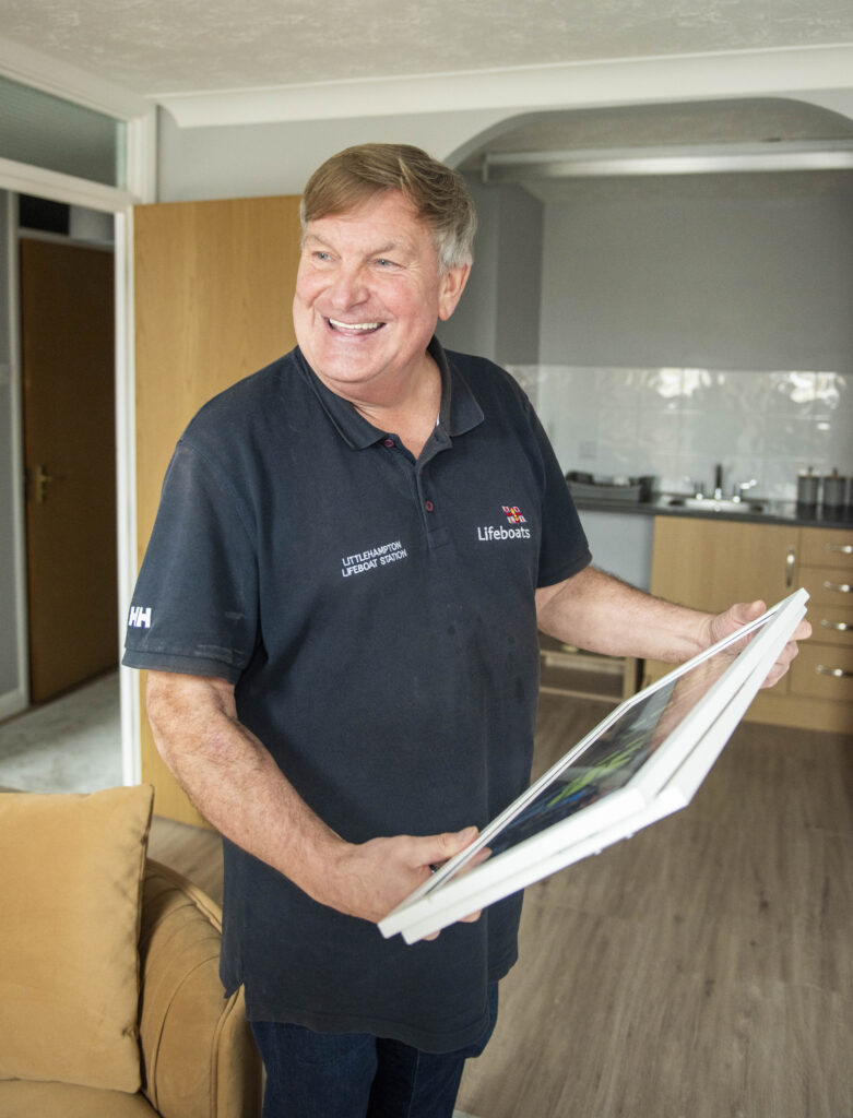 RNLI volunteer retiree in apartment holding picture of the RNLI team